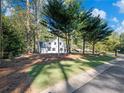 White farmhouse nestled among lush trees with a neatly manicured lawn at 3563 Denby Dr, Snellville, GA 30039