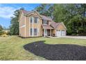 Tan two story house with a two car garage and landscaped yard at 4996 Gracehill Rd, Stonecrest, GA 30038