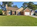 Brick and vinyl sided house with a 2-car garage and well-manicured lawn at 6300 Phillips Ct, Lithonia, GA 30058