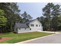 Rear view of farmhouse with additional garage and lush landscaping at 16 Berkshire Ln, Hiram, GA 30141