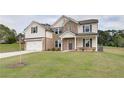 Two story brick home with white accents, a three car garage and manicured lawn at 205 Blanton Ln, Stockbridge, GA 30281