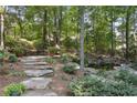 Stone steps lead to a serene pond, nestled in a wooded backyard at 1400 Lamont Cir, Dacula, GA 30019