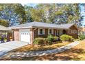 Brick ranch house with an attached garage, landscaping, and a paved driveway at 2639 Odum St, Snellville, GA 30078