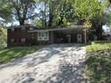 Brick ranch house with carport, large yard, mature trees, and landscaping at 1318 Shoreham Dr, Atlanta, GA 30349
