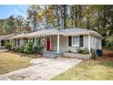 Gray brick ranch home with red door, updated landscaping and driveway at 2435 Wood Valley Dr, Atlanta, GA 30344
