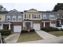 Two-story townhome with gray and yellow siding, attached garage, and landscaping at 832 Arbor Gate Ln # 832, Lawrenceville, GA 30044