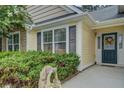 House exterior featuring a pale yellow facade, dark gray shutters, and a teal front door at 3894 Potomac Walk Ct, Loganville, GA 30052