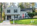 Newly renovated house with gray siding, a pink door and landscaped lawn at 6677 Eastbriar Dr, Lithonia, GA 30058