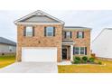 Two-story brick home with a white garage door and landscaping at 205 Montgomery Dr, Stockbridge, GA 30281