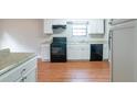 Efficient kitchen with white cabinets, black appliances, and light wood flooring at 4480 Joseph Dr, Snellville, GA 30039