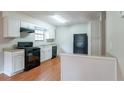 Efficient kitchen with white cabinets, black appliances, and light wood flooring at 4480 Joseph Dr, Snellville, GA 30039