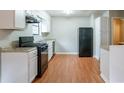 Efficient kitchen with white cabinets, black appliances, and light wood flooring at 4480 Joseph Dr, Snellville, GA 30039