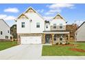 Two-story home with brick and white siding, a covered porch, and a two-car garage at 3952 Adler Cir, Buford, GA 30519