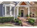 Inviting front entry with a covered porch, brick steps, and lush landscaping at 77 Mcdonald Sw St, Marietta, GA 30064