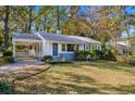 Front view of a cozy white house with a covered porch and landscaped yard at 2627 Elsinore St, East Point, GA 30344