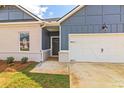 Front entrance with gray door and white-framed windows, next to a two-car garage at 231 Orwell Dr, Social Circle, GA 30025