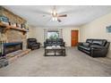 Living room with stone fireplace, leather furniture, and ceiling fan at 175 Highland Cir, Mcdonough, GA 30253