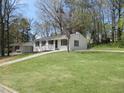 White ranch house with a spacious lawn and mature trees at 6325 Westbury Rd, Riverdale, GA 30274