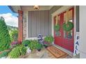 Inviting front porch with red double doors, stone flooring, and lush plants at 5035 Shade Creek Xing, Cumming, GA 30028