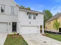 Two-story townhome with white and gray siding, two-car garage, and landscaped yard at 699 Sunstone Ln, Lawrenceville, GA 30043