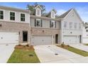 Three-unit townhome building, featuring brick and gray siding, two-car garages, and landscaped yards at 689 Sunstone Ln, Lawrenceville, GA 30043