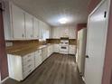 Galley kitchen with white cabinets and wood-look floors at 997 Chartley Sw Dr, Lilburn, GA 30047