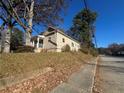 Side view of tan house with street view, trees, and leaves on the ground at 1480 Belmont Sw Ave, Atlanta, GA 30310