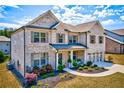 Two-story brick home with a three-car garage and manicured landscaping at 571 Wagon Hill Ln, Sugar Hill, GA 30518