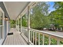 Inviting front porch with white railings, offering a view of the tree-lined street at 1230 Scenic Brook Sw Trl, Conyers, GA 30094