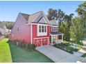 A two-story red home stands with its attached garage, viewed from an angle showcasing the front and side at 100 Academy Ln, Canton, GA 30114