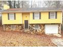 Ranch-style home with yellow siding, stone accents, and attached garage at 1593 Cherry Hill Ln, Conyers, GA 30094