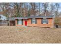 Brick ranch house with red door, attached carport, and landscaped yard at 2707 Crescendo Nw Dr, Atlanta, GA 30318