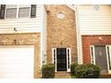 Townhome entrance with a black door, brick accents, and landscaping at 247 Brookview Dr, Riverdale, GA 30274