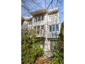 White three-story townhome with dark windows and a balcony at 9129 Selborne Ln, Chattahoochee Hills, GA 30268