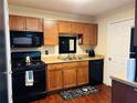 Compact kitchen with wood cabinets, black appliances, and a decorative floor mat at 2711 Greystone Ct, Austell, GA 30106