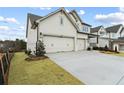 Three-car garage with a light beige exterior and neatly landscaped yard at 227 Wild Ginger Bnd, Woodstock, GA 30188