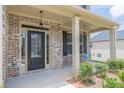 Inviting front porch with brick columns, a black front door, and comfy seating at 171 Osier Dr, Mcdonough, GA 30252