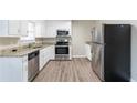 Modern kitchen featuring white cabinets, granite countertops, stainless steel appliances, and wood-look flooring at 1151 Martin Rd, Stone Mountain, GA 30088
