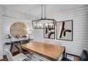 Dining area featuring a wood table, modern chandelier, and shiplap walls adorned with artwork at 6097 Marigold Way, Atlanta, GA 30349