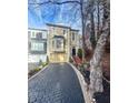 Townhome with paver driveway, landscaping, and trees in the background at 9015 Niblick Dr, Alpharetta, GA 30022