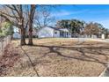 Side view of a charming white ranch home showcasing its fenced yard and mature trees at 7017 Ray St, Riverdale, GA 30274