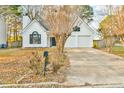 Inviting white home with paved driveway, attached two-car garage, and landscaping at 4021 E Meadow Dr, Duluth, GA 30096