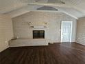 Living room featuring wood-look floors, a brick fireplace with a mantel, and vaulted ceilings at 90 Skyline Dr, Hampton, GA 30228