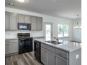 Kitchen with gray cabinets, granite countertops, black appliances, and an island at 338 Forkview Dr, Lawrenceville, GA 30044