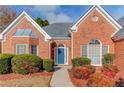 Front entryway with blue door, arched windows, and manicured shrubs at 1545 Great Oaks Dr, Lawrenceville, GA 30045