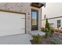 Front door with glass panels, black frame, and a brick exterior wall with modern light fixture at 1332 Koa Se Ct # 100, Smyrna, GA 30080