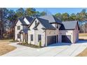 Side view of a brick home with dark gray roof, three-car garage, and large driveway at 824 Braselton Hwy, Lawrenceville, GA 30043