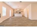 Open-concept kitchen and dining area with wood-look flooring and modern light fixtures at 1628 Fuma Leaf Way, Mcdonough, GA 30253