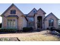 Elegant brick home with arched entryway, multiple windows, and landscaping at 3229 Carmichael Pl, Duluth, GA 30097