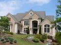 Beautiful brick home with arched entryway, lush landscaping, and a gray roof at 3229 Carmichael Pl, Duluth, GA 30097
